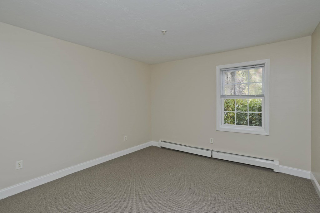 a bedroom with white walls and a window