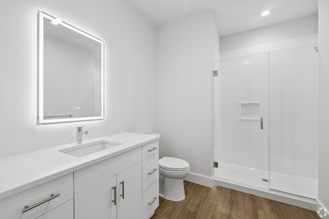 A white bathroom with a sink, toilet, and shower.