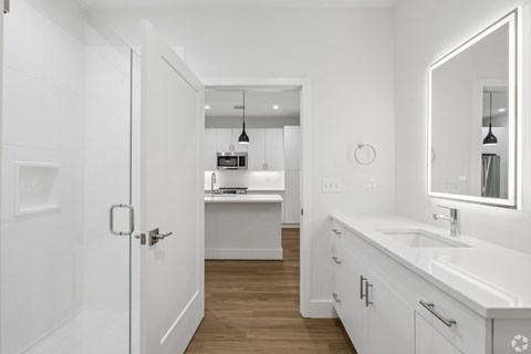 A white bathroom with a sink, mirror, and a door.