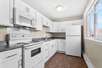 A kitchen with white appliances and cabinets.