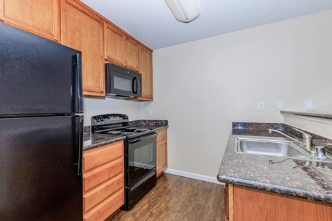A kitchen with a black refrigerator, microwave, and stove.