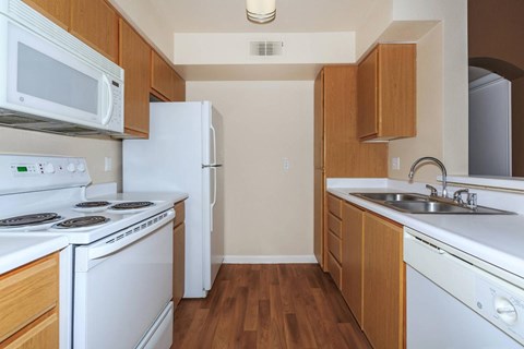 A kitchen with white appliances and wooden cabinets.