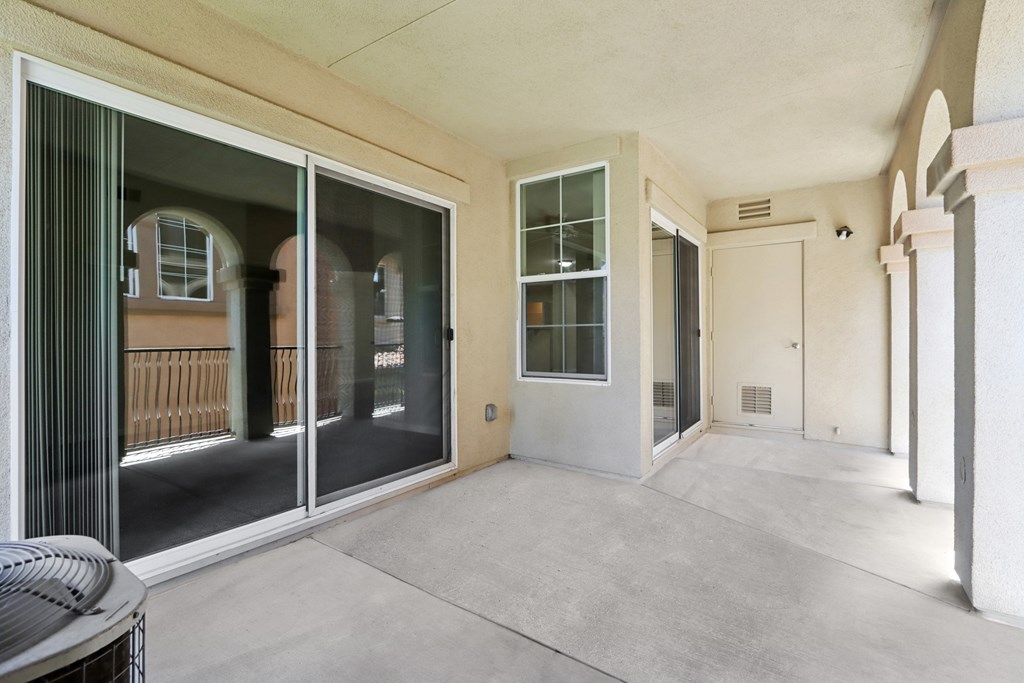 A patio with a sliding glass door and a table.