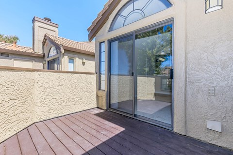 A patio with a wooden deck and sliding glass doors.