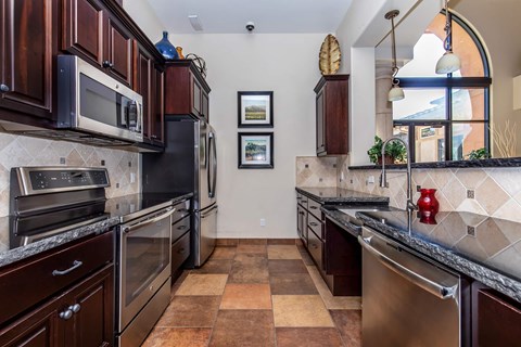 A kitchen with brown cabinets and a tile floor.
