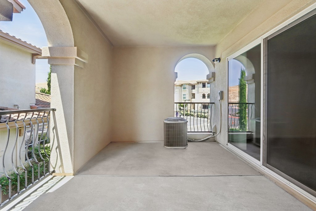 A patio with a white railing and a white air conditioning unit.