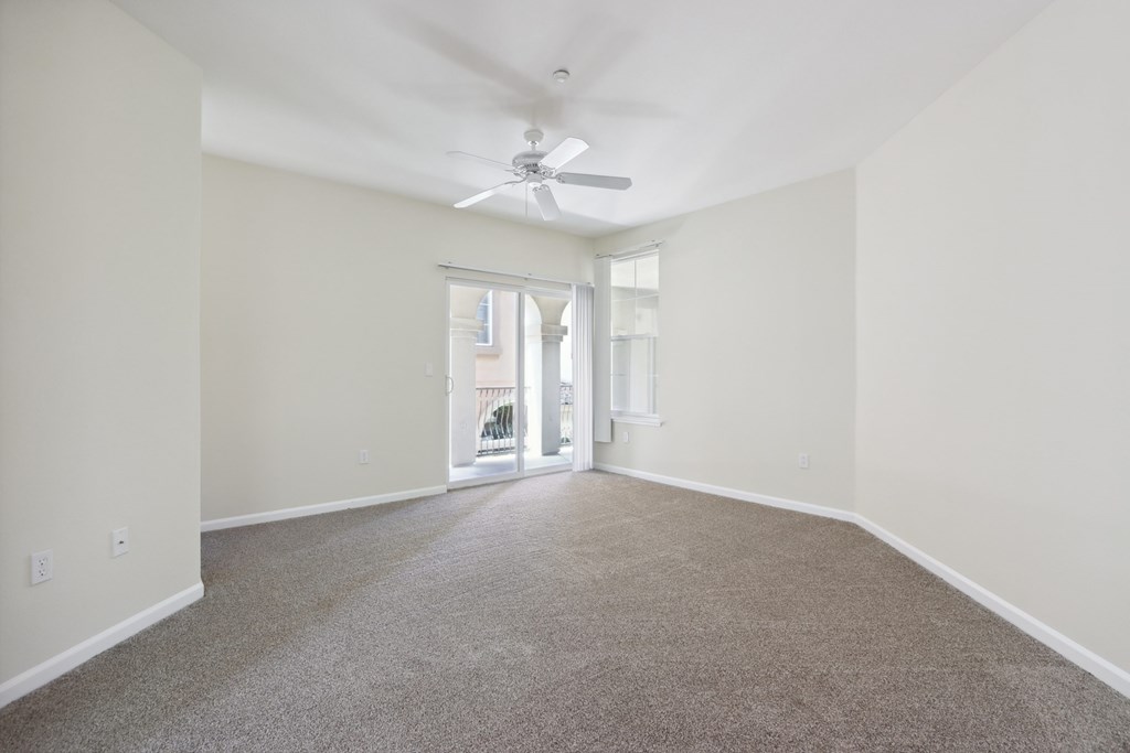 A spacious room with a ceiling fan and carpeted floor.