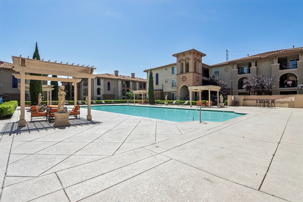 A pool surrounded by a patio with a building in the background.