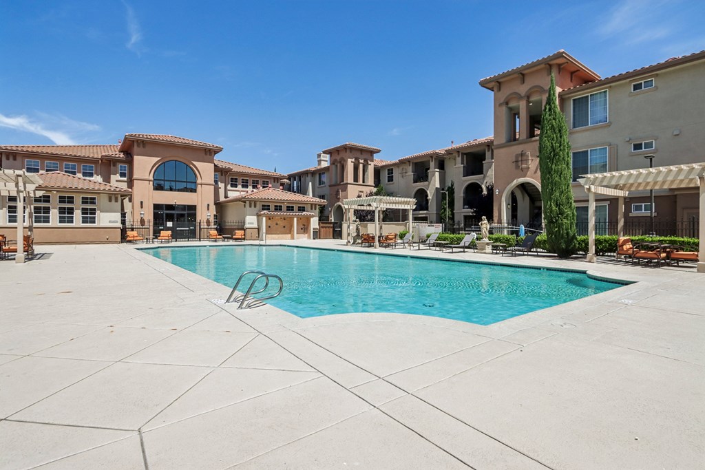 A large swimming pool in front of a building with a clear blue sky.