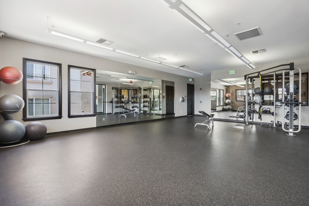 A spacious gym with a variety of equipment and a large mirror on the wall.