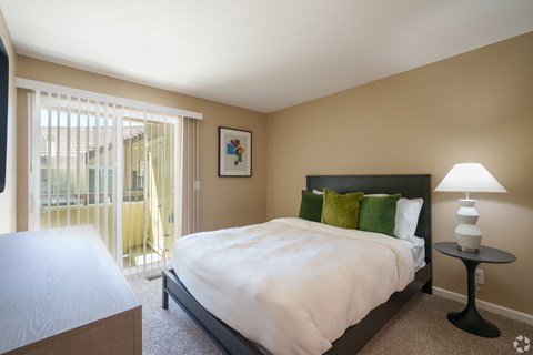 A bedroom with a large bed and a lamp on a side table.