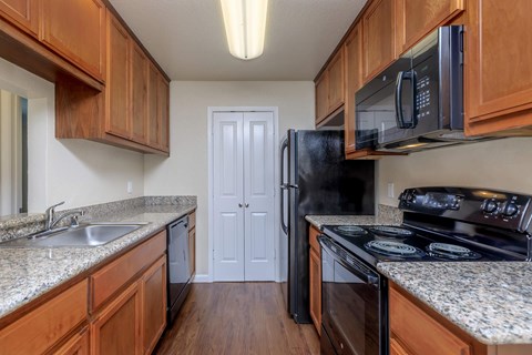 A kitchen with wooden cabinets and a black refrigerator.