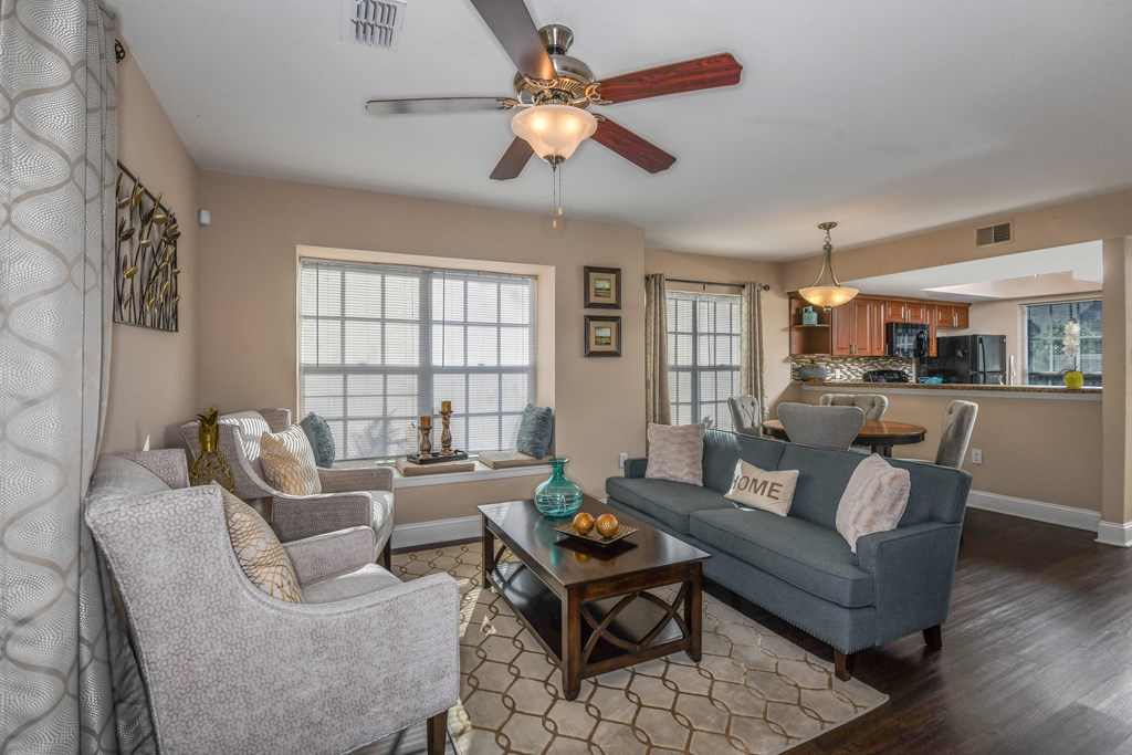 Bloomingdale Woods Apartments Valrico Florida Model Apartment Living Room Area with Couch and 2 Lounge Chairs and Ceiling Fan with View towards Kitchen and Eat-In area with dining table and chairs