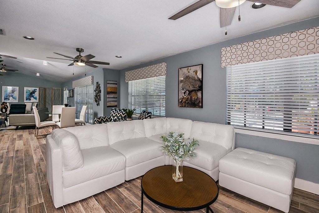 Side View 2 of Brookside Manor renovated and redecorated clubhouse lounge with comfortable couches and lounge chairs, tastefully decorated with inspired art pieces, with wood plank flooring