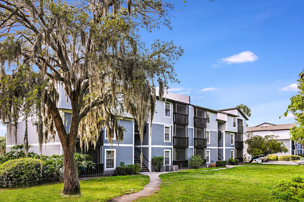 View of Brookside Manor Apartment Building, with green grass and mature tree on a sunny bluebird day