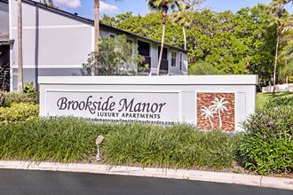 View of Brookside Manor Community Welcome Sign framed by lush green landscaping