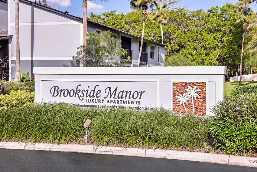 View of Brookside Manor Community Welcome Sign framed by lush green landscaping - Photo Gallery 1
