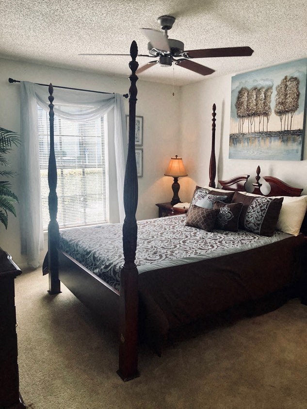 a bedroom with a four poster bed and a ceiling fan