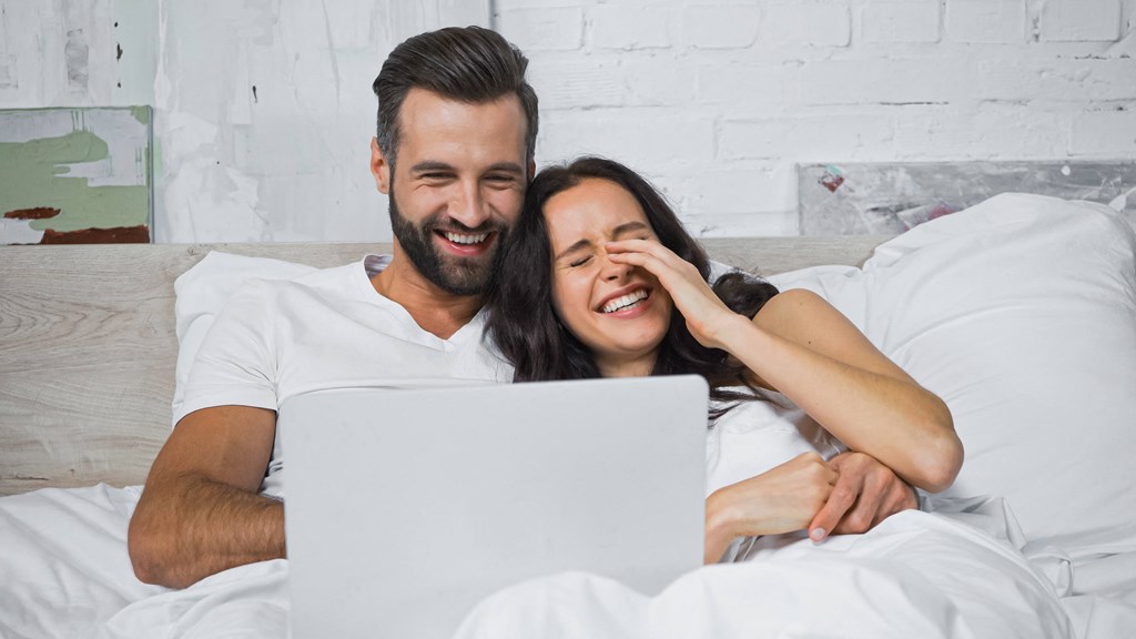 Couple watching movie on laptop and laughing
