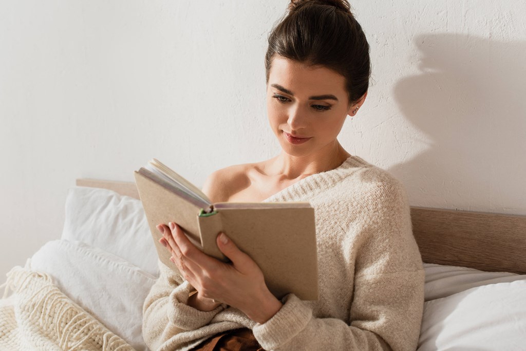 woman reading a book in bed