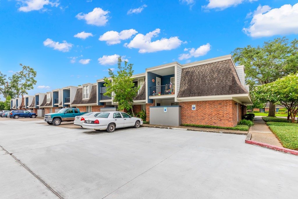 A parking lot with a building and cars parked in front.
