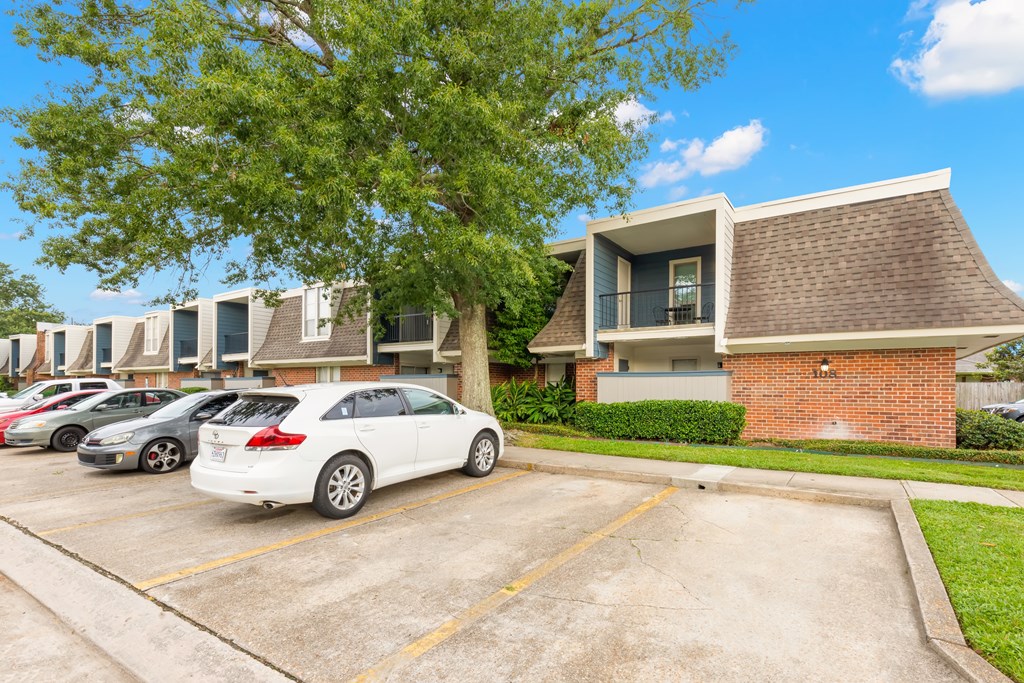 A white car is parked in a parking lot in front of a building.