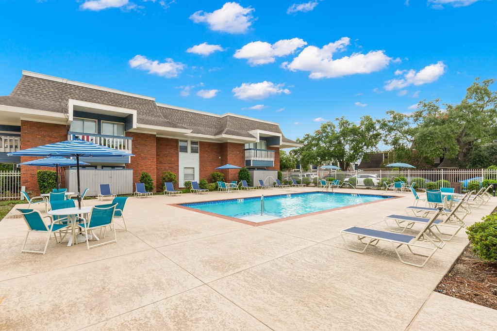 A pool area with chairs and a building in the background.