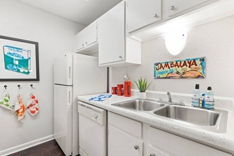 a white kitchen with a sink and a refrigerator