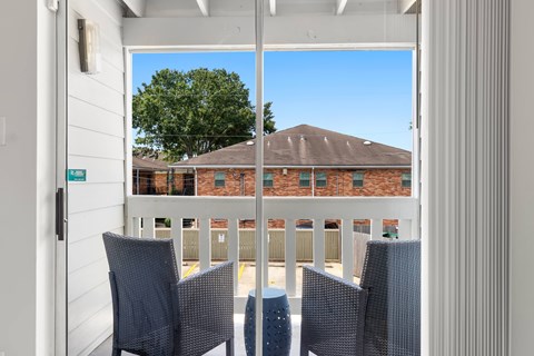 A balcony with chairs and a view of a building.