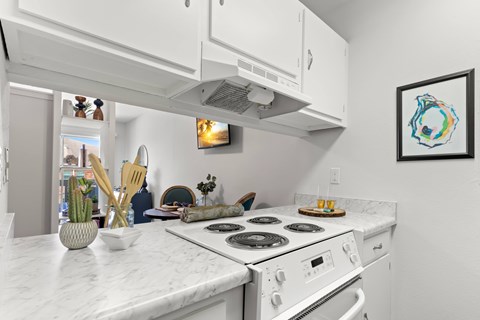 A white kitchen with a stove top oven and a fridge.