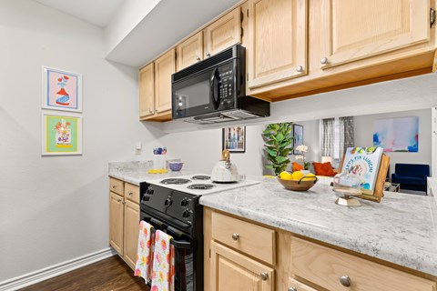 A kitchen with wooden cabinets and a black microwave above the stove.