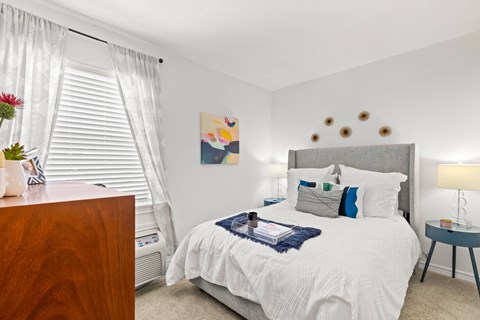 A bedroom with a white bed and a wooden dresser.