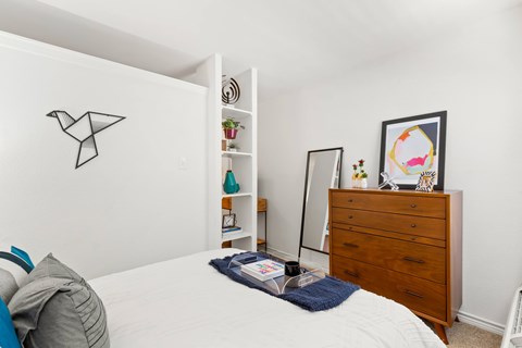 A bedroom with a bed, a dresser, and a mirror.