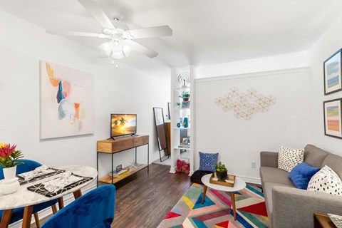 A living room with a white ceiling fan and a painting on the wall.