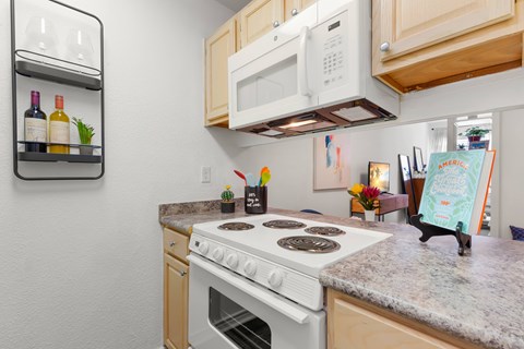 A kitchen with a white stove top oven and a white microwave above it.