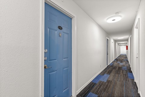 A long hallway with a blue door on the left.