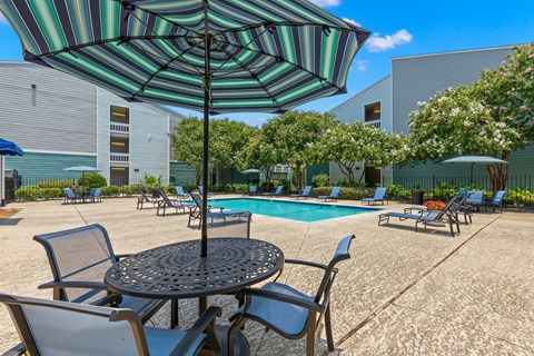 A patio with a table, chairs and an umbrella.