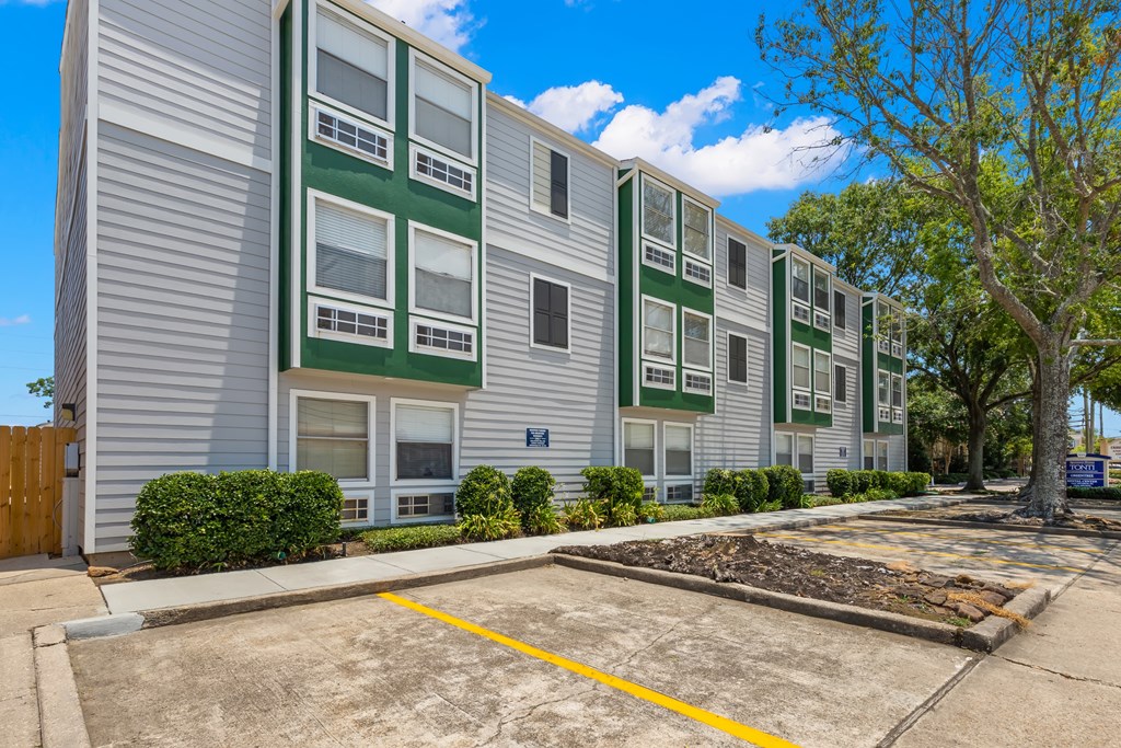 Apartment building with a parking lot in front.