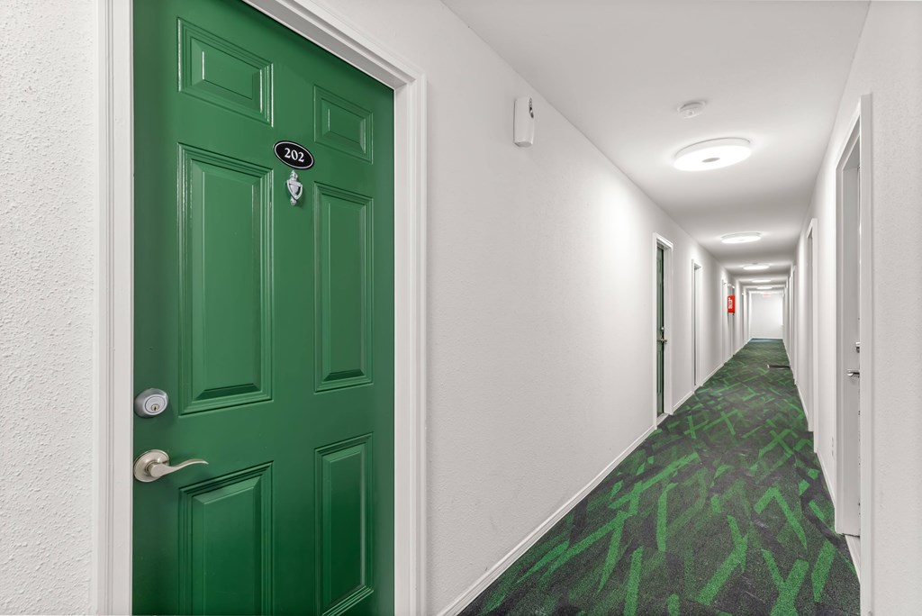 A hallway with a green door and carpet.
