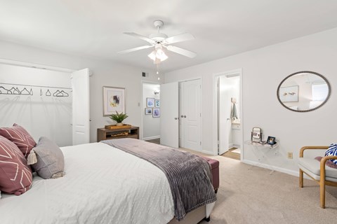 A bedroom with a bed, a chair, and a mirror on the wall.