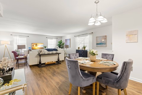 A well-lit, modern dining room with a round table and grey chairs.