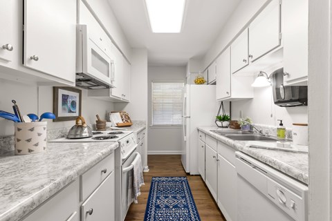 A kitchen with white cabinets and a marble countertop.