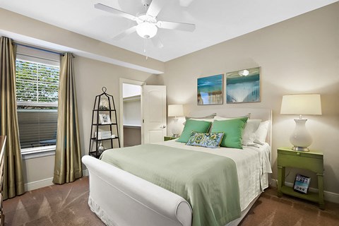 A bedroom with a large bed and a ceiling fan.