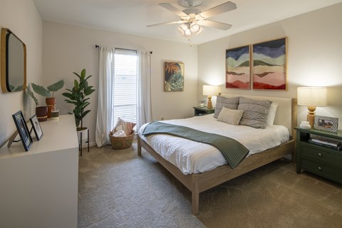 A bedroom with a large bed and a ceiling fan.