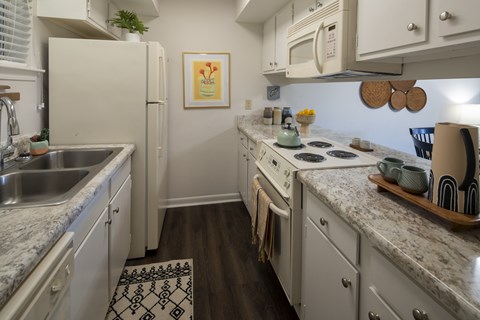 A kitchen with a white fridge, white cabinets, and a white microwave.