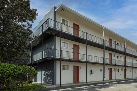 A modern apartment building with balconies and red doors.