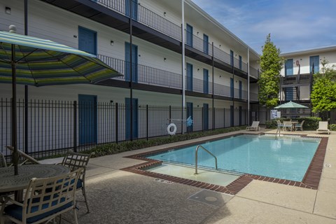 A pool area with a table and chairs and umbrellas.