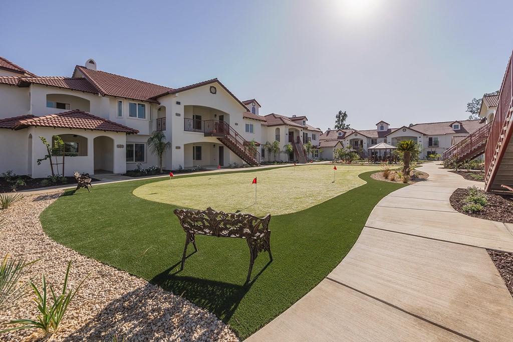 A sunny day at a residential area with houses and a bench.