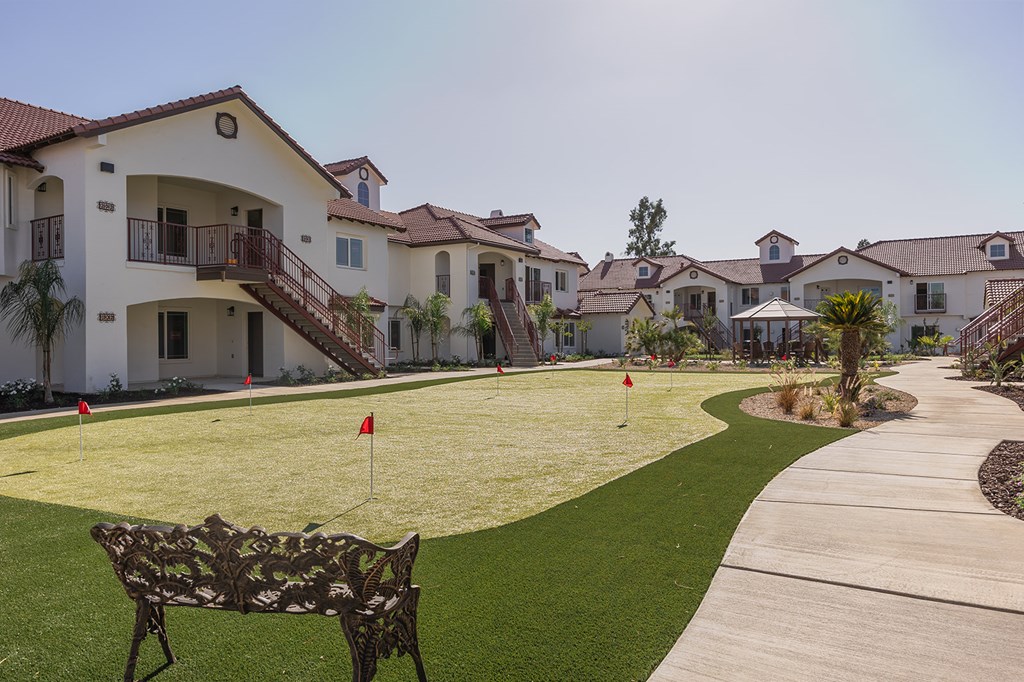 A park area with a bench and a golf hole with a flag.