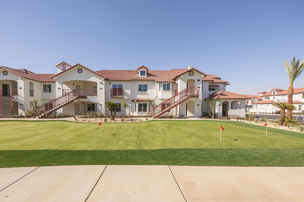 A large house with a red roof and a green lawn in front.
